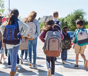 Kids wearing backpacks walking together to school